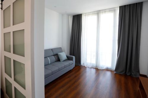 a living room with a blue couch in front of windows at Hotel Homey Kobuleti in K'obulet'i