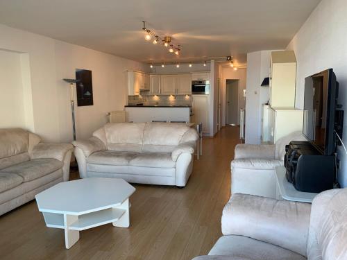 a living room with white couches and a kitchen at Mare Nostrum 0402 in Nieuwpoort