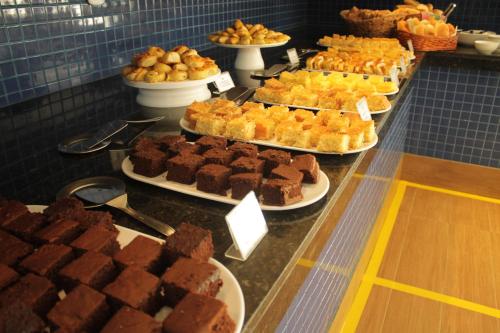 a buffet filled with different types of cakes and brownies at Hit Hotel in Salvador