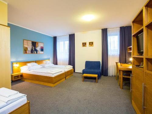 a hotel room with two beds and a desk at Hotel Trend in Plzeň