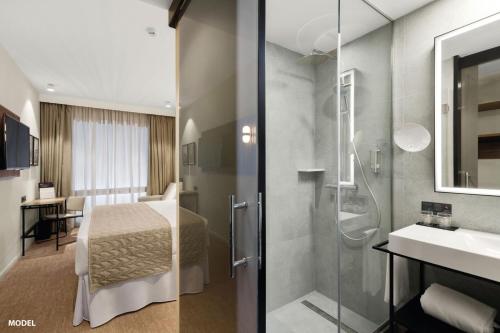 y baño con cama, ducha y lavabo. en Riu Plaza Manhattan Times Square en Nueva York