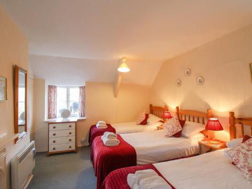 a bedroom with two beds with red blankets at Lower Farm Cottage in Weymouth