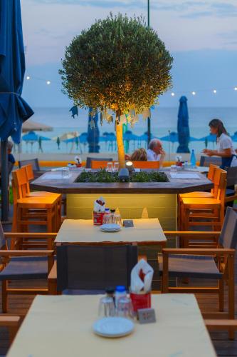 a restaurant with tables and chairs and a tree at Elite City Resort in Kalamata
