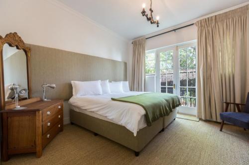 1 dormitorio con cama, espejo y ventana en Green Elephant Backpackers, en Ciudad del Cabo