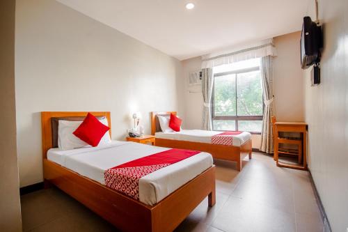 sypialnia z 2 łóżkami i oknem w obiekcie Capital O 719 Fuente Oro Business Suites w Cebu