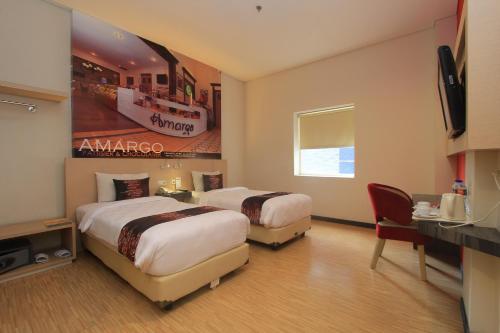 a hotel room with two beds and a desk at Hotel Promenade Cihampelas in Bandung
