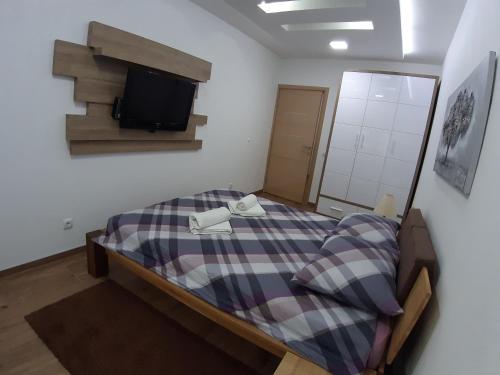 a bedroom with a bed with a tv on the wall at Serbian home, Gandijeva 162 in Belgrade