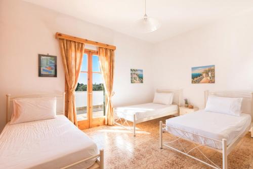 two beds in a room with a window at Villa Dina Chalikounas Corfu in Halikounas