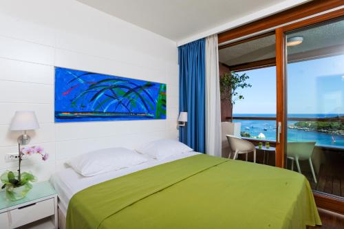 Maistra Select All Suite Island Hotel Istra في روفينج: غرفة نوم بسرير اخضر ونافذة كبيرة
