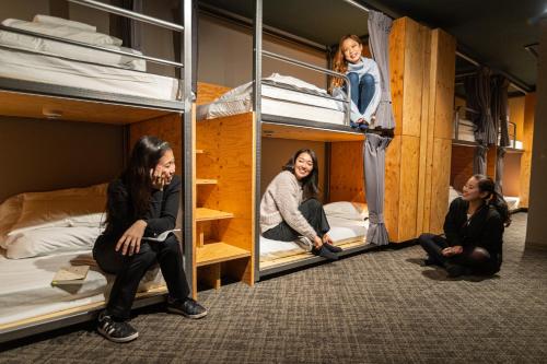 Tre donne sono sedute nei loro letti a castello di Wise Owl Hostels River Tokyo a Tokyo