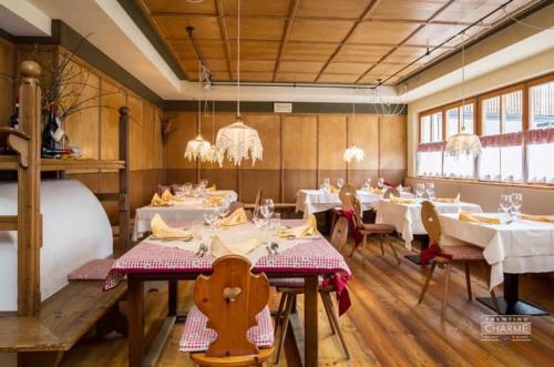 um restaurante com mesas e cadeiras brancas e lustres em Chalet Prà delle Nasse em San Martino di Castrozza