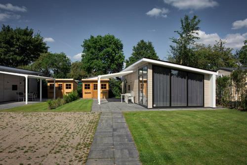 a house with a lawn in front of it at Recreatiepark Jachthaven De Veerstal Lathum - Luxe Chalet in Lathum