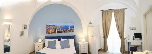 Chiaia Suites في نابولي: غرفة نوم مع سرير ذو شكل قوس مع وسائد زرقاء وبيضاء