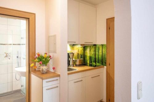 uma cozinha com um lavatório e um balcão com flores em Gästehaus Grünäugl am See em Gstadt am Chiemsee