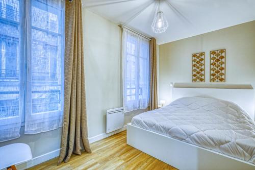 une chambre avec un lit et de grandes fenêtres dans l'établissement Manarola, F3 à deux pas de Montparnasse, à Paris