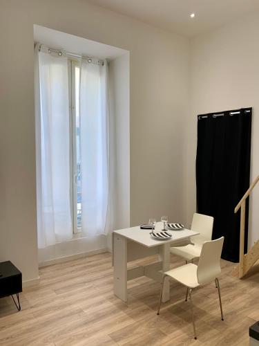 een witte kamer met een tafel en 2 stoelen bij Gustave 2 in Nice