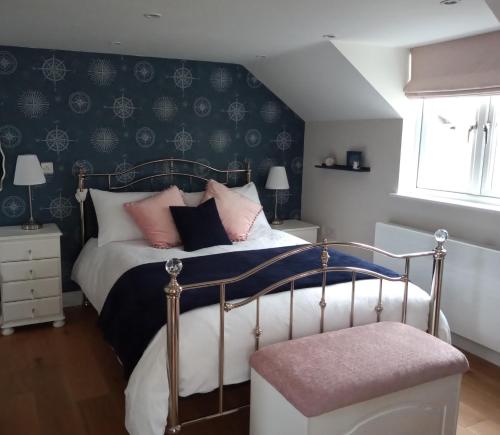 een slaapkamer met een bed met roze kussens bij The Captains Quarters, Woolsery in Bideford