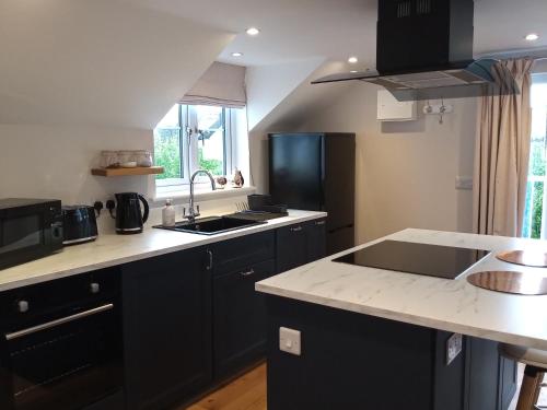 a kitchen with black cabinets and a white counter top at The Captains Quarters, Woolsery in Bideford