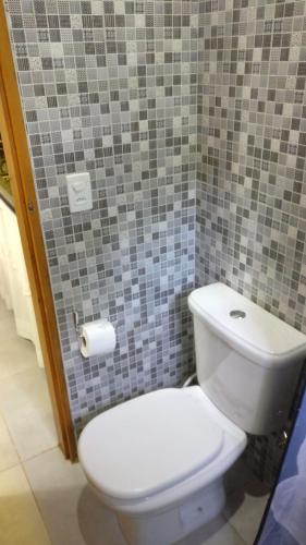 a bathroom with a white toilet in a tile wall at Chalé Juliet in Pirenópolis