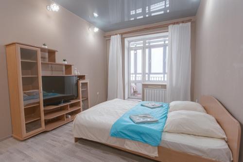 a bedroom with a bed and a tv and a window at Welcome Home Apartments Dalnevostochnaya 106 in Irkutsk