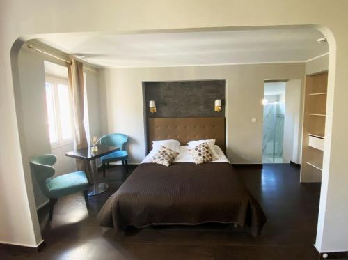 1 dormitorio con 1 cama grande, mesa y sillas en Hôtel La Villa d'Eze, en Èze