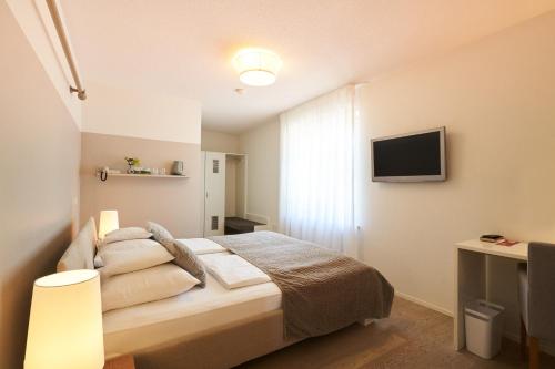 a bedroom with a bed and a flat screen tv at Gästehaus am Wasserschloss & Restaurant Wasserschloss Inzlingen in Inzlingen