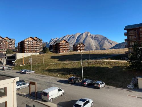 a street with cars parked in a parking lot with mountains at Studio les toits du Devoluy in Le Dévoluy