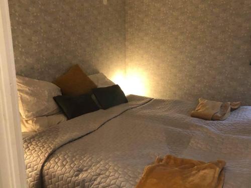 um quarto com uma cama grande com lençóis brancos e almofadas em Strandnära Stuga Vänersnäs em Vargön
