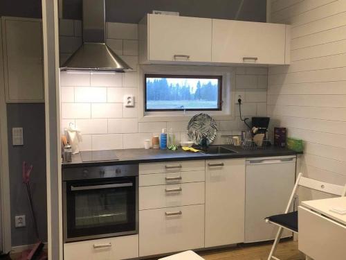 a kitchen with white cabinets and a window at Strandnära Stuga Vänersnäs in Vargön