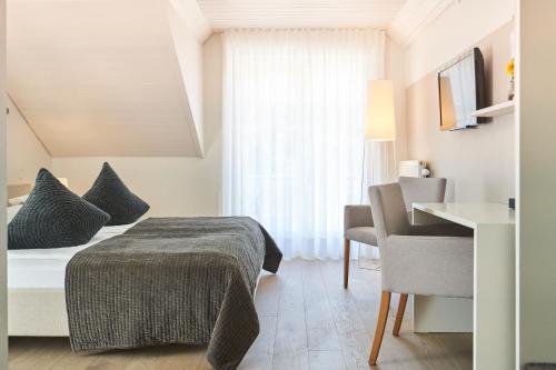 a bedroom with a bed and a table and a chair at Gästehaus am Wasserschloss & Restaurant Wasserschloss Inzlingen in Inzlingen