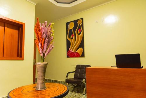 an office with a desk and a vase of flowers on a table at AVISHA TOWN HOTEL in Kigali