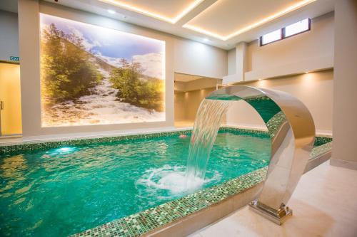 a swimming pool with a waterfall in a house at SREBRNA PLANINA Spa & Resort in Kopaonik