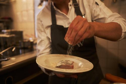 a person in a kitchen holding a plate of food at Gästehaus am Wasserschloss & Restaurant Wasserschloss Inzlingen in Inzlingen