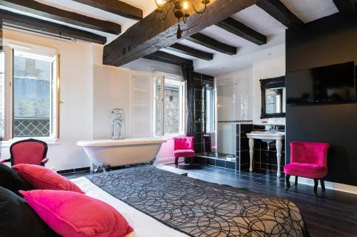 ein Badezimmer mit rosa Stühlen und einer Badewanne in der Unterkunft Logis Hotel Restaurant Le Cheval Blanc in Bléré