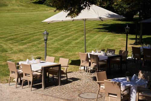 a group of tables and chairs with an umbrella at Gästehaus am Wasserschloss & Restaurant Wasserschloss Inzlingen in Inzlingen