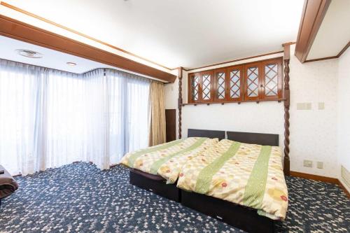 um quarto com uma cama e uma grande janela em ふたばホテル em Tóquio
