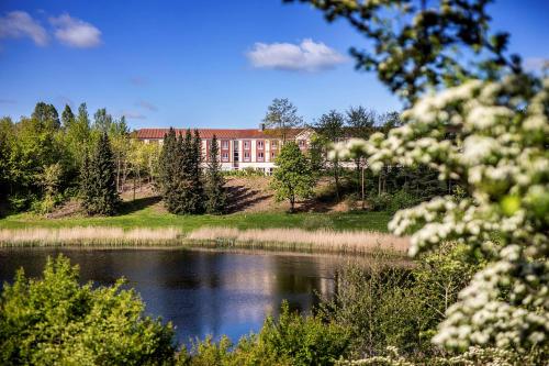 a large building on a hill next to a lake at Scandic Roskilde Park in Roskilde