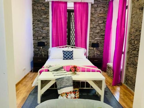 Techas City Center Luxurious Suite في برايا: غرفة نوم مع ستائر وردية وسرير