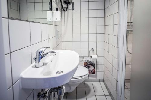 uma casa de banho branca com um lavatório e um WC em Scandic The Mayor em Aarhus