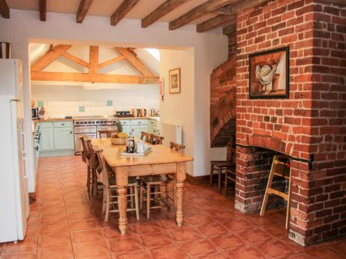 a kitchen with a wooden table and a brick fireplace at Stockbatch Granary in Shrewsbury