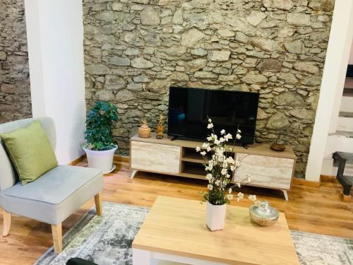 a living room with a tv and a stone wall at Techas City Center Luxurious Suite in Praia
