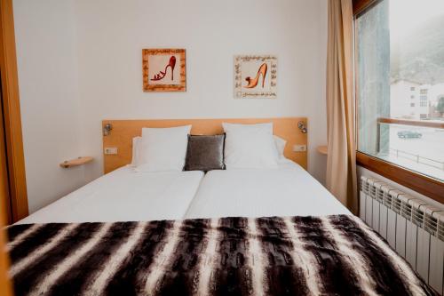 a bed with a black and white comforter and a window at Sol Tarter 4-7 in El Tarter