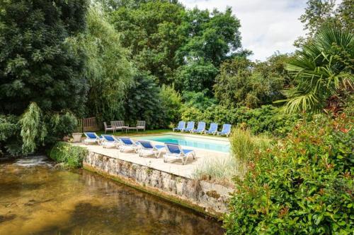 a swimming pool with lounge chairs next to a river at la ferme, Coeur De Combray in Ernes
