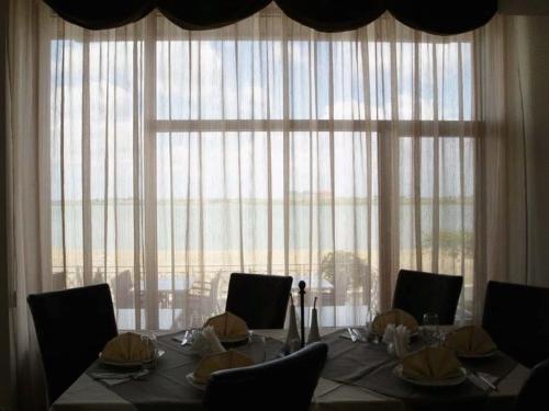 a dining room table with chairs and a large window at Verona Villas Complex in Mamaia Sat/Năvodari