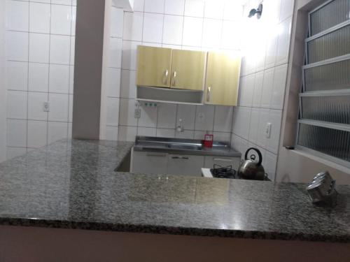 a kitchen with a counter with a sink and cabinets at Apartamentos de Verão in Tramandaí