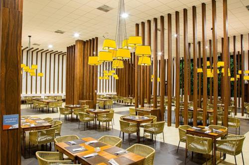 a dining room with tables and chairs and yellow chandeliers at Taua Hotel e Convention Alexania in Alexânia