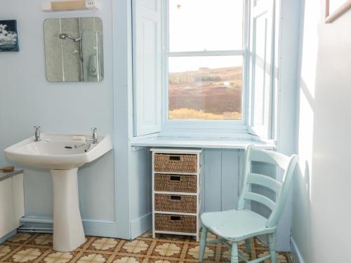 a bathroom with a sink and a window and a chair at St Agnes in Duns