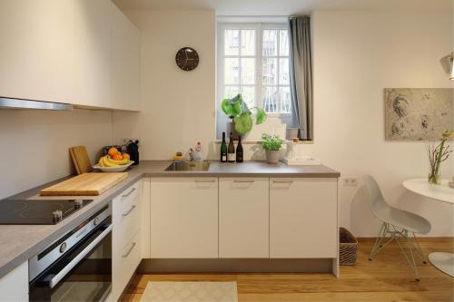 - une cuisine avec des placards blancs et un évier dans l'établissement Boutique Apartments Freiburg - Elsa, à Fribourg-en-Brisgau