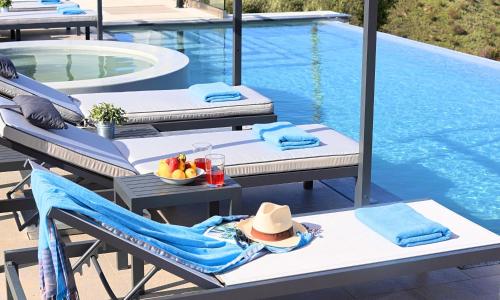 a woman in a hat sitting on a chair next to a pool at Mistral Suite Heated Pool in Georgioupoli