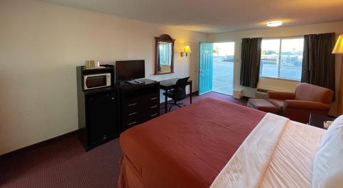 Habitación de hotel con cama, escritorio y TV. en Antilley Inn, en Abilene